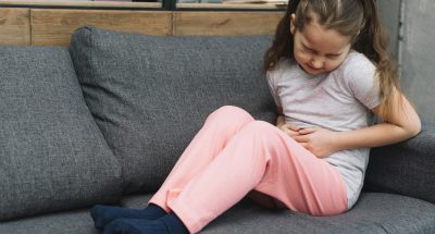 sick-girl-sitting-gray-sofa-suffers-from-stomach-pain-home