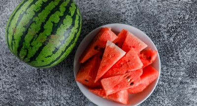 Watermelon with slices on grey grunge background, flat lay.