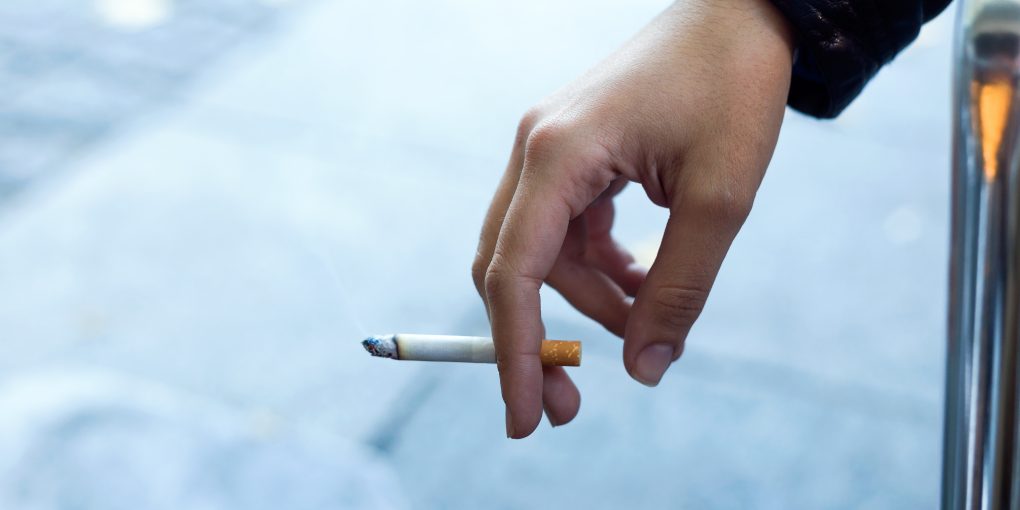 Close up of womans hand with cigarette in the street.