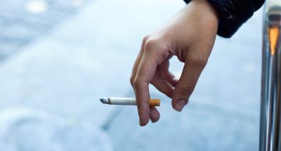 Close up of womans hand with cigarette in the street.