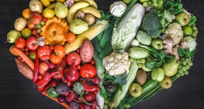 Heart made of fresh vegetables and fruit on wooden background, top view.