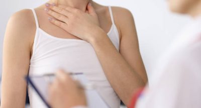Woman hand showing sore neck at doctor appointment closeup. Thyroid disease concept