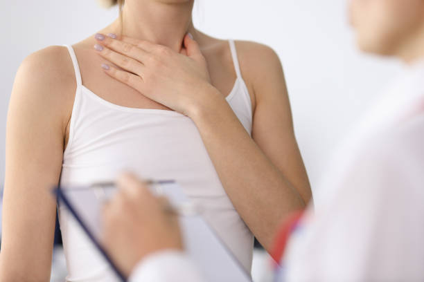 Woman hand showing sore neck at doctor appointment closeup. Thyroid disease concept