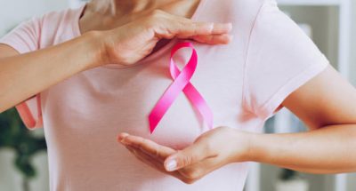 Asian woman show pink ribbon as sign of October Breast Cancer Awareness month
