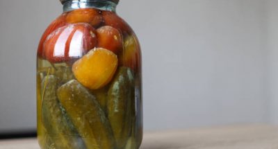 spoiled can of vegetable seaming. Glass jar with homemade pickled tomatos and cucumbers with white fungus and mold