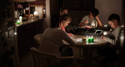 Family spending time together during an energy crisis in Europe causing blackouts. Kids drawing in blackout.