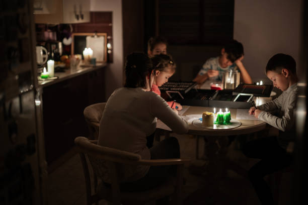 Family spending time together during an energy crisis in Europe causing blackouts. Kids drawing in blackout.